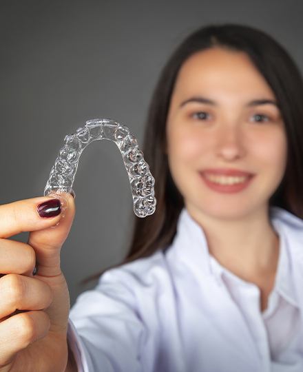 Hand holding an Invisalign clear aligner tray