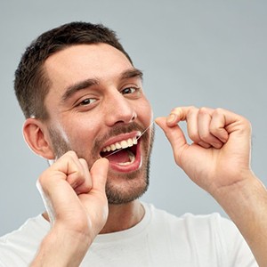 Man flossing to prevent dental emergencies in Tyler