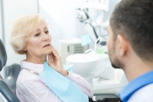 senior woman talking to her dentist about her poorly fitting dentures 